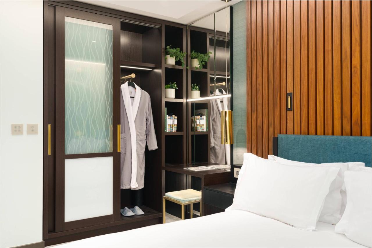 Middle Eight - Covent Garden - Preferred Hotels And Resorts Лондон Екстериор снимка The photo shows a cozy hotel room featuring a neatly made bed with white bedding. On the side, there is a wardrobe with sliding glass doors. Inside the wardrobe, a light-colored robe is hanging, and there are shelves with small plants and toiletries 