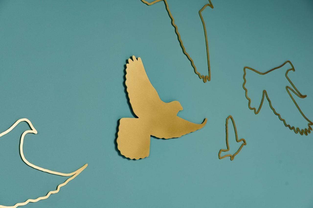 Middle Eight - Covent Garden - Preferred Hotels And Resorts Лондон Екстериор снимка The photo shows a collection of metallic gold bird silhouettes against a solid turquoise background. The birds are depicted in various positions and styles, showcasing different species and flight postures. Some silhouettes are more detailed, while o